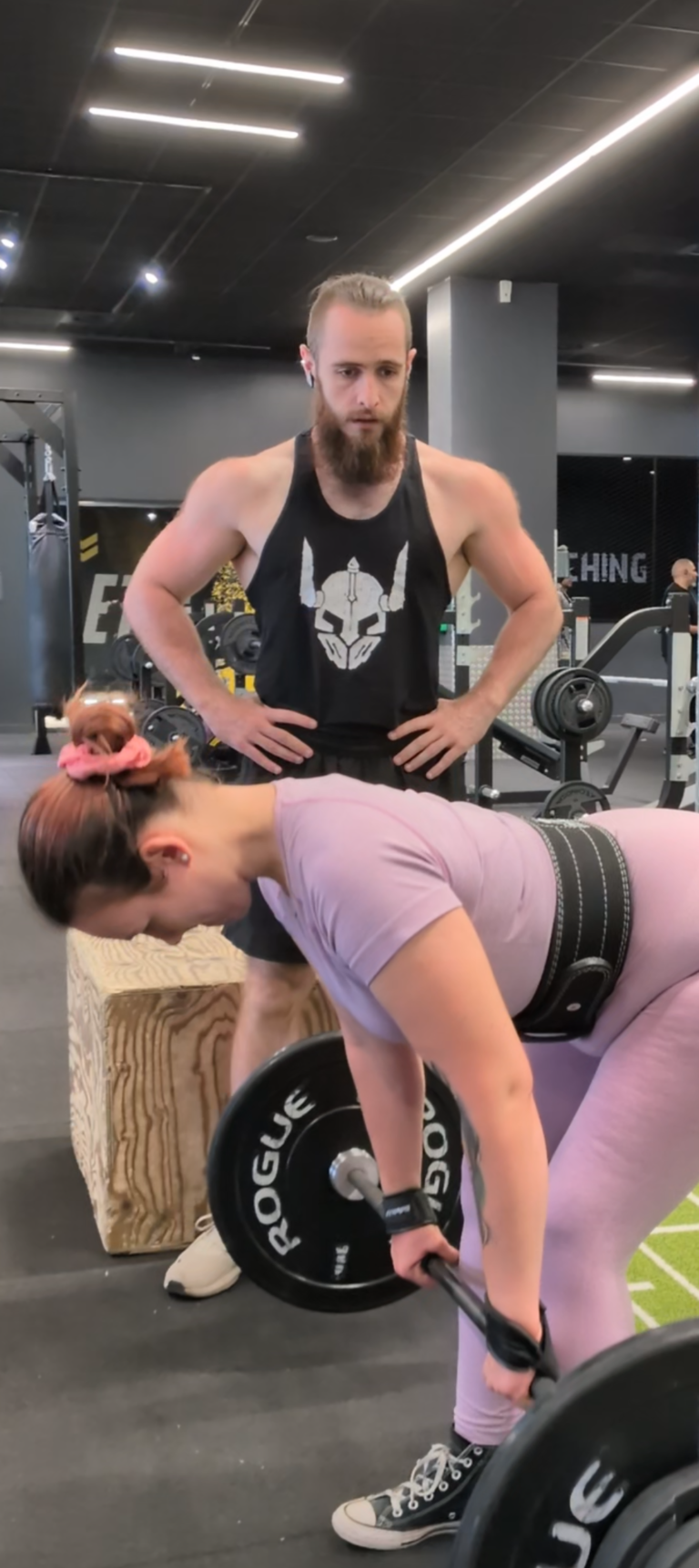 Une femme fait des exercices RDL à la salle de sport avec un entraîneur observant
