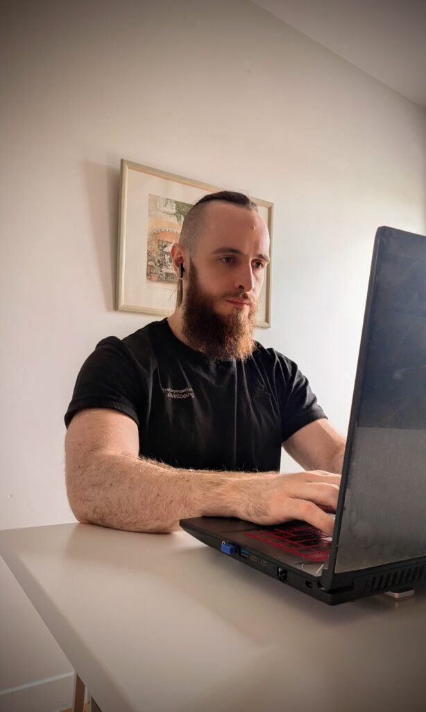 Homme barbu utilisant un ordinateur portable dans un bureau moderne